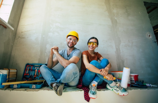 Modern happy young couple in love in casual clothes during new home repair or renovation of walls with a lot of tools for this