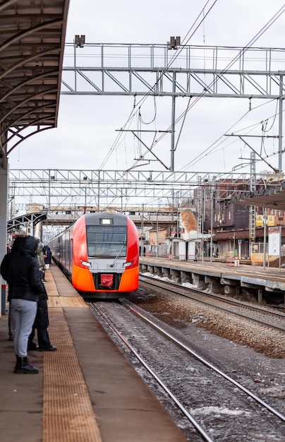 現代の高速列車はプラットホームに沿って速く動く人々は駅で列車を待っています