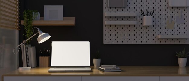 Modern home workstation at night with lights from table lamp laptop mockup and stationery