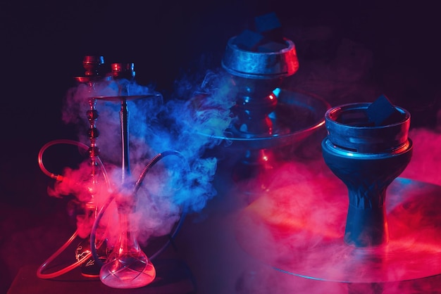 Photo modern hookah shisha on a smoky black background with neon lighting and smoke collage