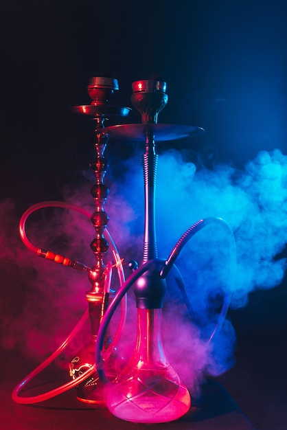 Modern hookah, shisha on a smoky black background with neon lighting