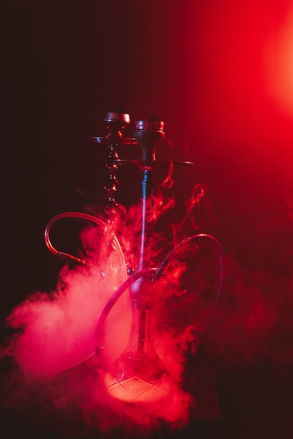 Modern hookah, shisha on a smoky black background with neon lighting