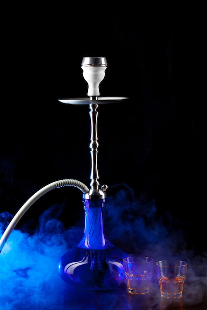 Modern hookah with smoke in dark club light close up