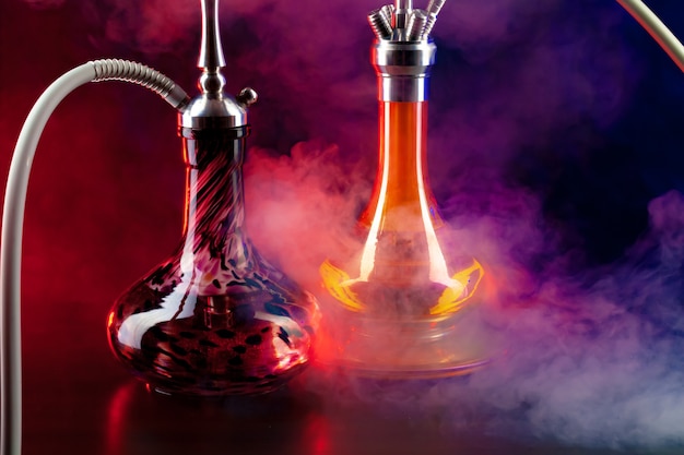 Modern hookah with smoke in dark club light close up