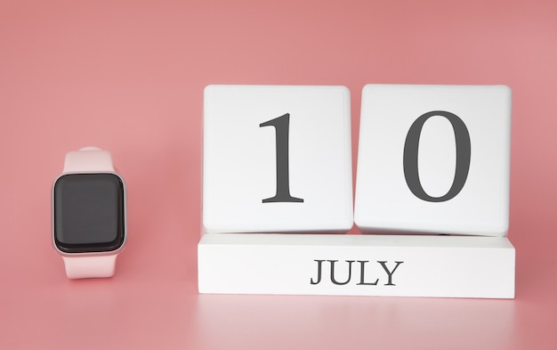 Modern horloge met kubus kalender en datum 10 juli op roze muur. Concept zomertijd vakantie.