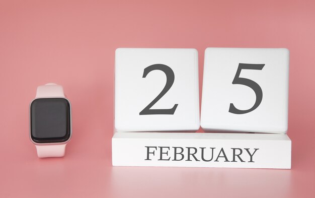 Modern horloge met kubuskalender en datum 25 februari op roze achtergrond. Concept wintervakantie.