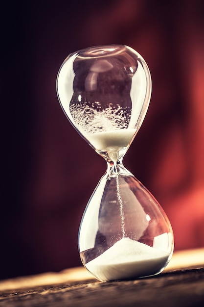 Modern hourglass in running time on wooden table