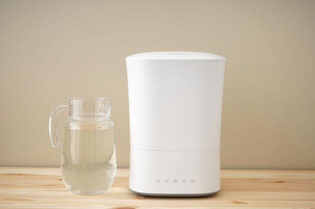 Modern humidifier and water decanter on a wooden table.