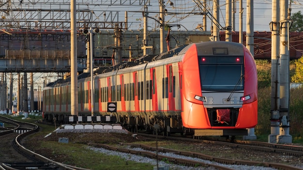 Modern intercity high speed train under the bridge on railroad at sunset