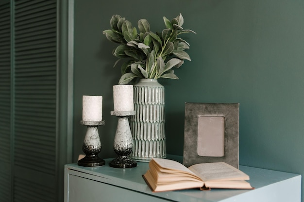 Modern interieur in smaragdgroene kleur met decorkaarsen boekenvaas met bloemen