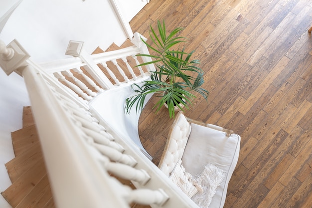 Modern interieur van een lichte kamer in een appartement met twee verdiepingen met decoratieve items in Bali-stijl met een balkon. witte muren, houten vloeren en vintage meubels