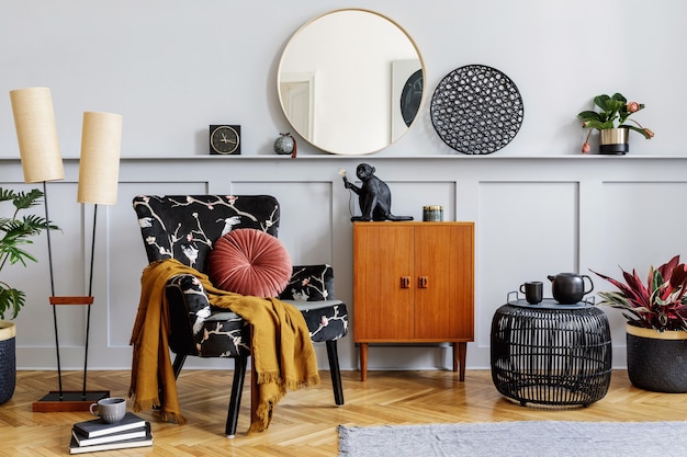 Modern interieur van woonkamer met design fauteuil, houten vintage commode, houten lambrisering met plank, planten, kubus, tapijt, grijze muur, decoratie en persoonlijke accessoires in home decor.