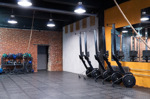 Modern interior of fitness gym with rowing machines and sport equipment