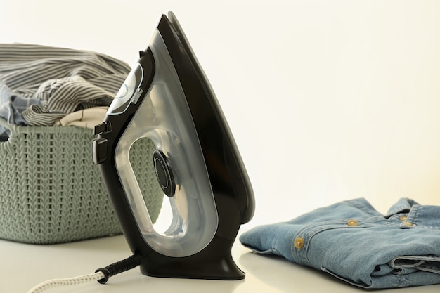 Modern iron and laundry on white table