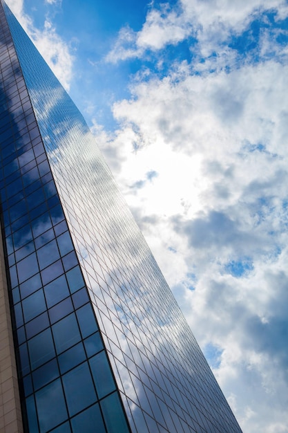 Modern kantoorgebouw van gerookt glas tegen een blauwe bewolkte hemel