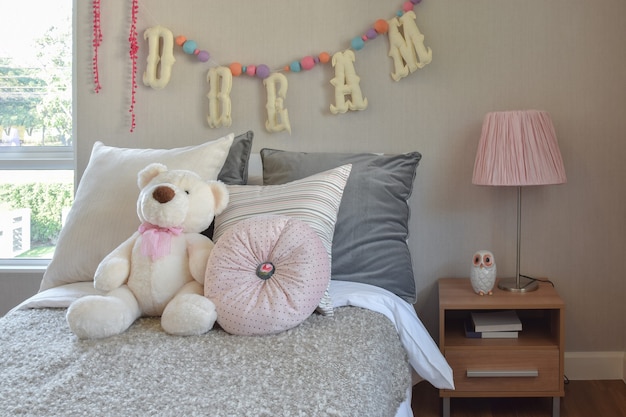 Modern kids room with doll and pillows on bed