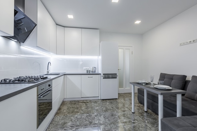 modern kitchen in light white tones with black marble tiles on the floor placed in a small apartment