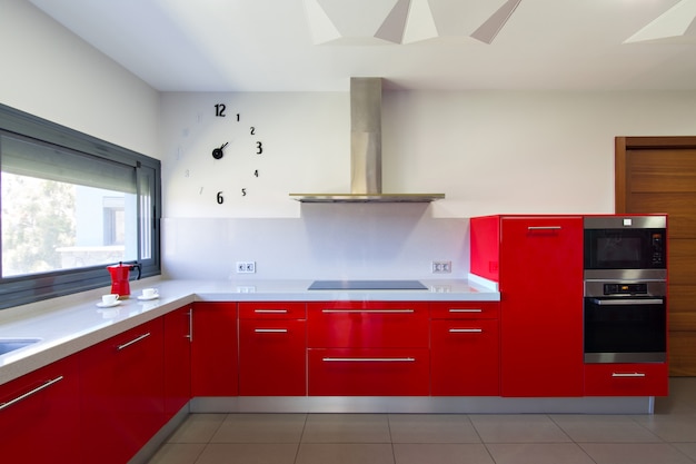 Modern kitchen in red, with exterior view. Interior design of house.