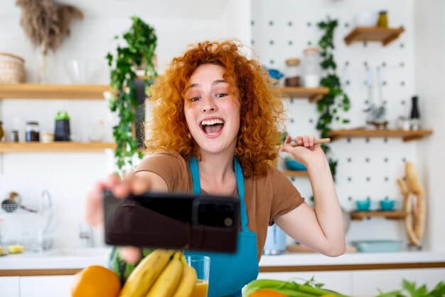 モダンなキッチンで料理をしながら自撮りする女性。輝くような笑顔と料理の美味しさを背景に、自己表現と料理の芸術性の完璧な融合を捉えています。