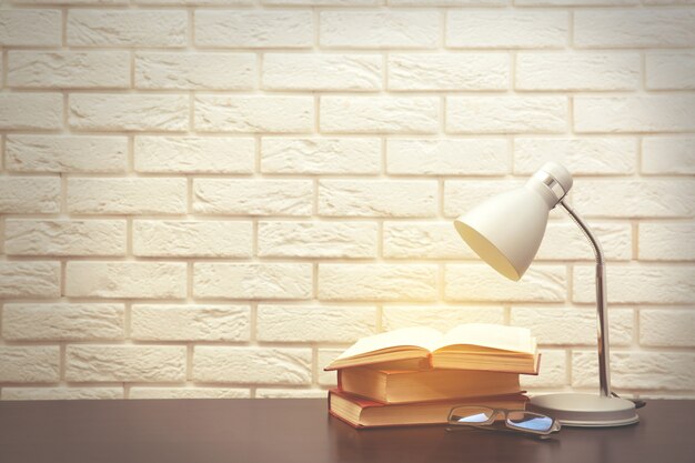 Modern lamp and books on the desk on white wall background