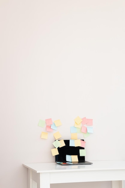 Modern laptop and different sticky notes on white wall