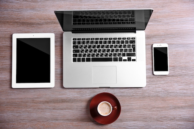 Modern laptop, smart phone and tablet with coffee cup on a wooden table