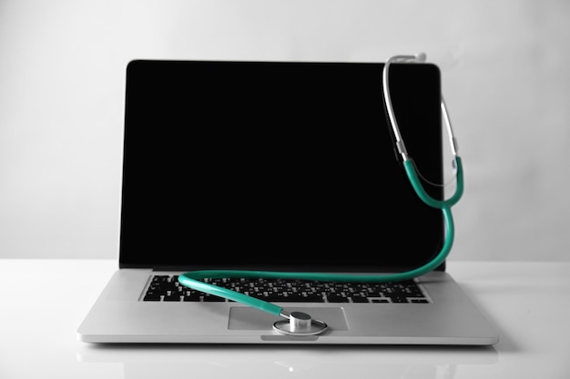 Modern laptop and stethoscope on white background