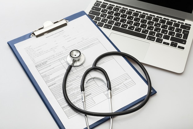 Modern laptop and stethoscope on wooden background