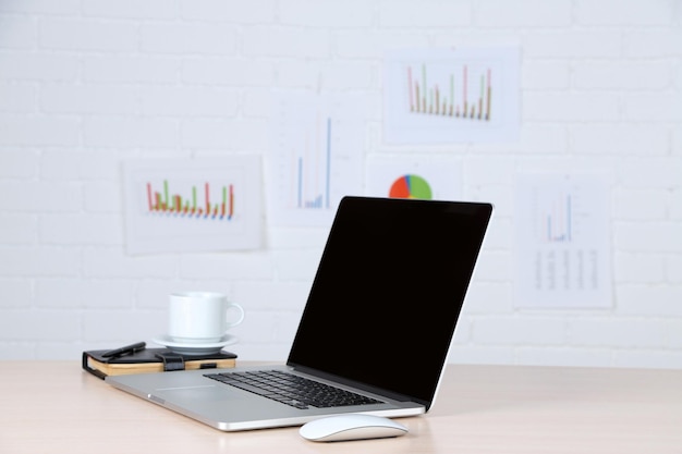 Modern laptop on table on white wall background