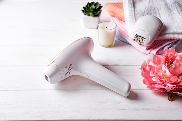 Modern laser epilator with bath accessories on white background.