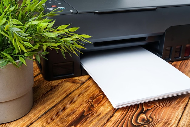 Modern laser printer with paper on wooden background
