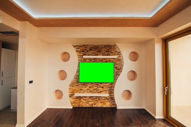 A modern lcd tv with green screen hanging on the wall