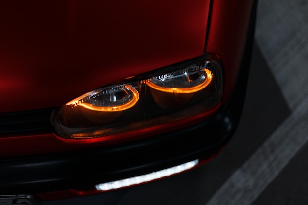 Modern led headlight on a tuned classic red car on the night street