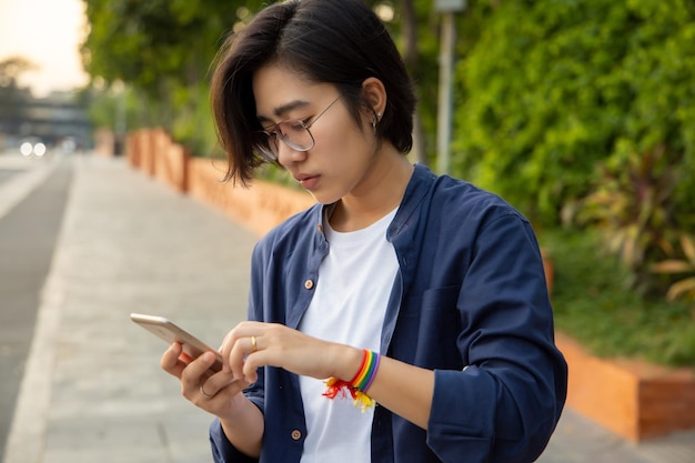 Modern LGBT woman with ribbon symbol using smartphone concept of LGBT or LGBTQ people community friends partner lgbt rights campaign equality same sex marriage sex preference diversity