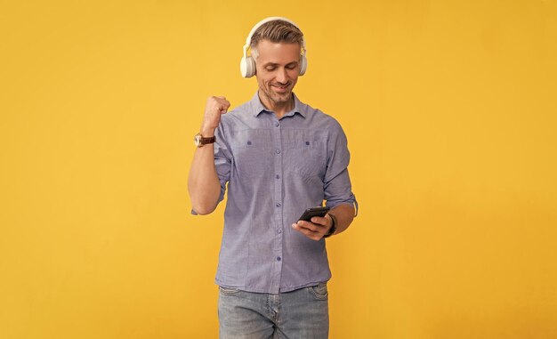 Modern life and lifestyle guy chatting in earphones musical\
playlist mobile music application new app happy guy in headphones\
use smartphone successful man listen music and hold phone