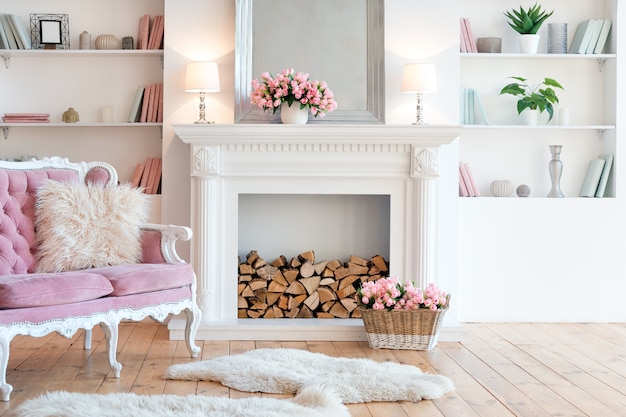 Modern light interior with fireplace, spring flowers and cozy pink sofa