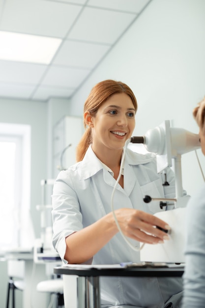 Modern light room. Red-haired ophthalmologist working in modern light room while examining girl