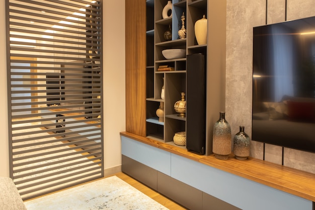 Фото Интерьер современной гостиной с телевизором, открытая система хранения, зеркальное панно с деревянными вставками на стене