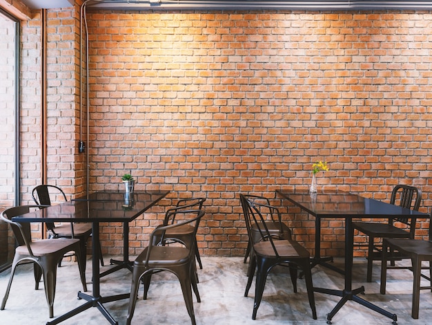 ブラックテーブルセットとレンガの壁を備えたモダンなロフトスタイルのカフェ