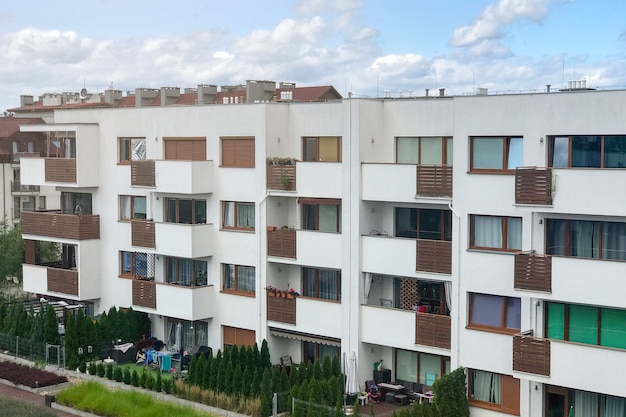 A modern low-rise home with small balconies and large windows set against a blue sky.