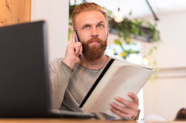 Photo modern man making a call while holding his notebook