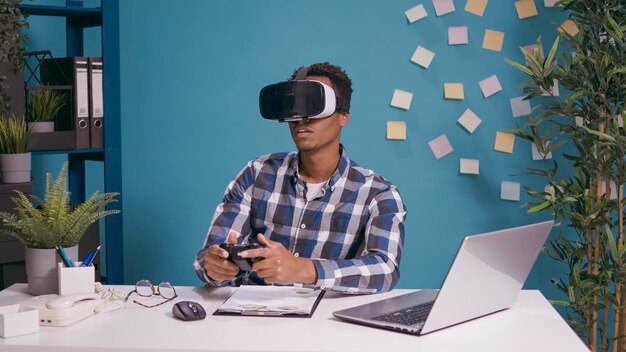 Modern man playing video games on vr goggles and console, using
virtual reality headset and controller for fun. person enjoying 3d
visual simulation glasses with joystick at desk.