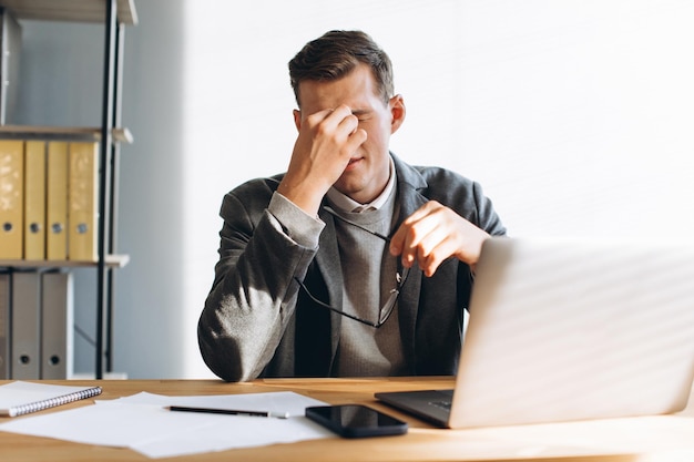 Modern man with glasses office worker tired at work