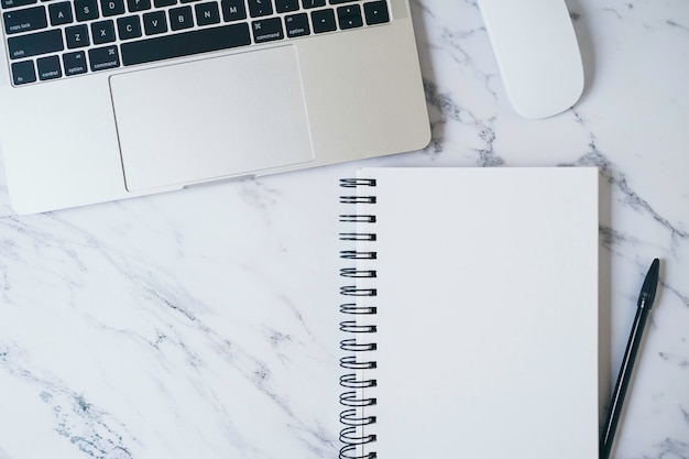 Photo modern marble office desk table with laptop and other supplies. blank white notebook page for input text or entry short note, copy space for creative content, ads and design . top view, flat lay.