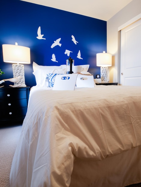 青い壁と白いリネンを備えたモダンなマスターベッドルーム。