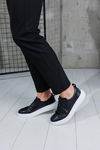 モダンなメンズ シューズ黒のパンツと黒のカジュアル スニーカーの男性の脚メンズ ファッショナブルな靴