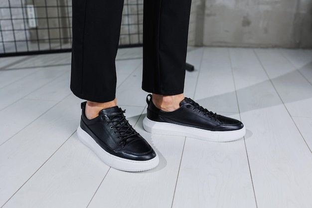 Modern men's shoes Male legs in black pants and black casual sneakers Men's fashionable shoes