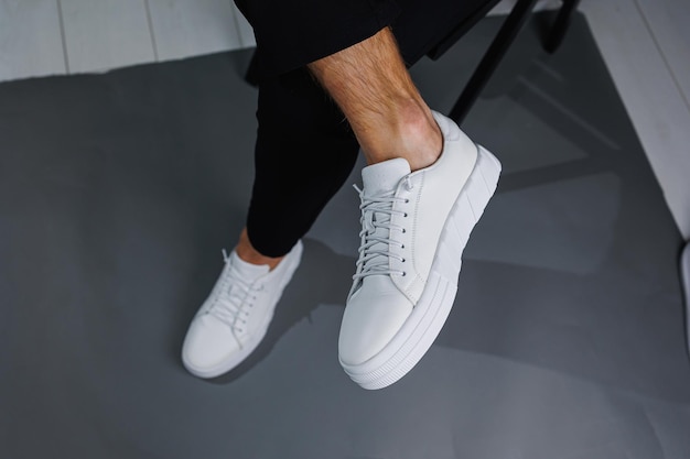 Modern men's shoes Male legs in black pants and white casual sneakers Men's fashionable shoes