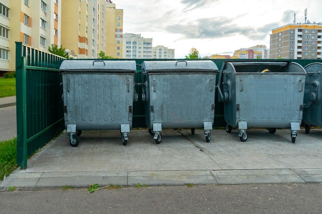 Modern metal containers for separate garbage collection Garbage cans in the city on the background of a house Environmental disaster problems of waste removal collection and disposal in a big city