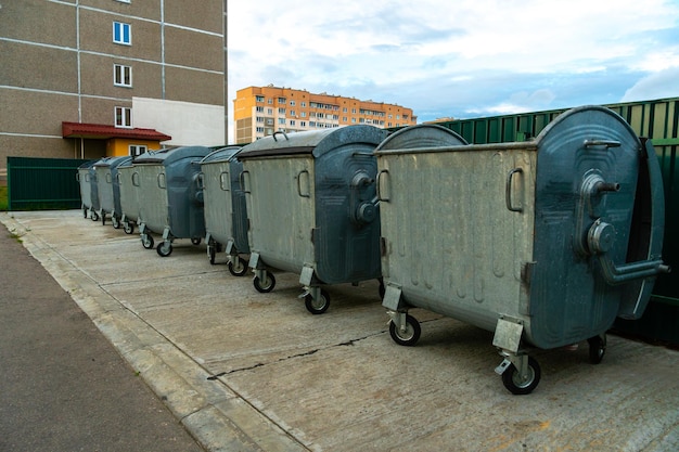 Modern metal containers for separate garbage collection Garbage cans in the city on the background of a house Environmental disaster problems of waste removal collection and disposal in a big city